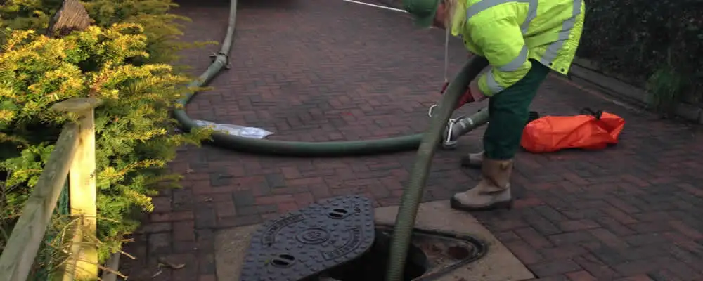 Septic tank cleaning technician servicing a septic tank with a vacuum hose in Fort Wayne, IN