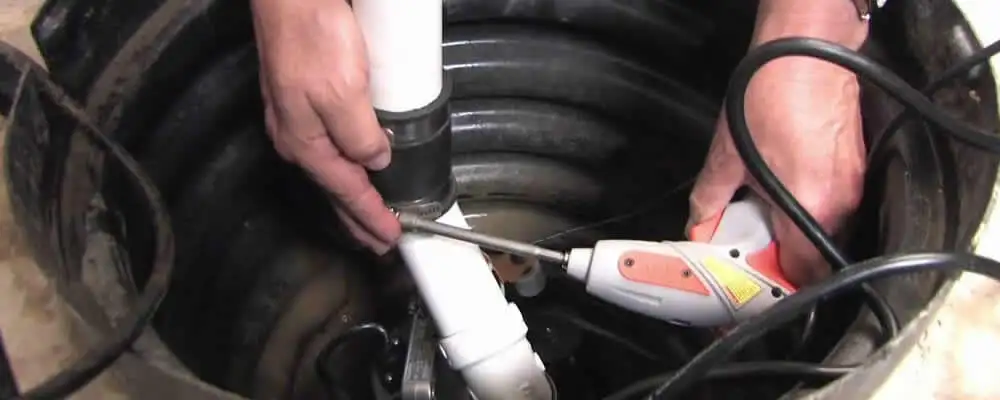Sump pump installation technician connecting PVC discharge piping in Fort Wayne, IN